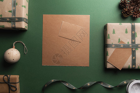 绿色背景的旧棕纸周围都是圣诞礼物和装饰品图片