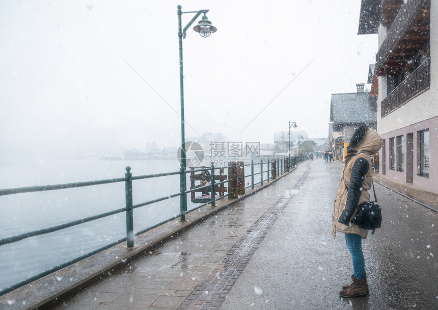 站在街上的女人看着雪花在阿斯特里亚的halst在冬天的雪图片