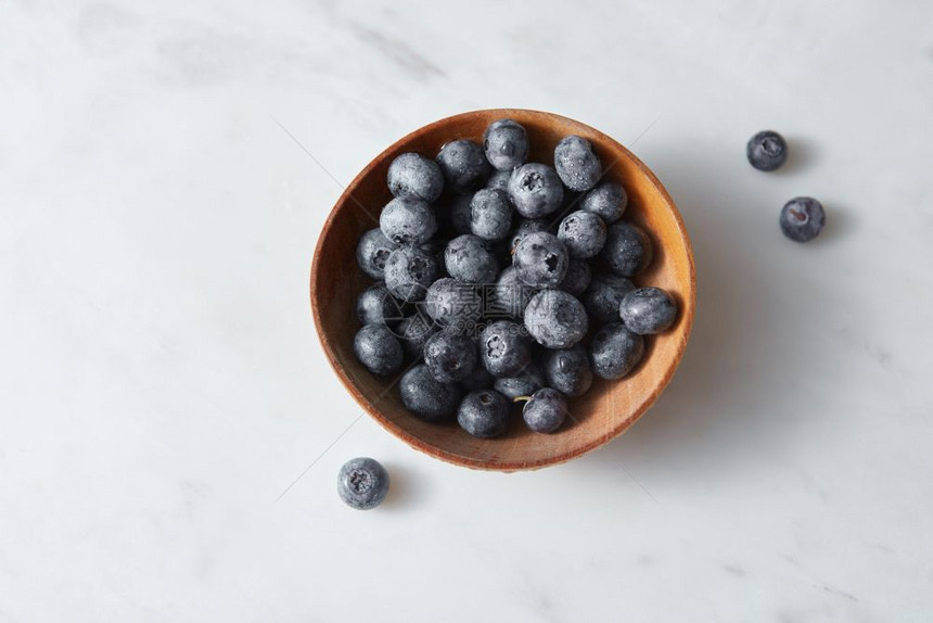 白色背景的新鲜天然有机浆果用于制作美味的天然果酱顶端视图有机新鲜的蓝莓放在白风景桌的木碗中复制空间图片