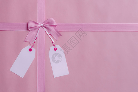 上方有一个礼物框粉色的弓和丝带还有两张空标签挂在弓上贺卡概念图片