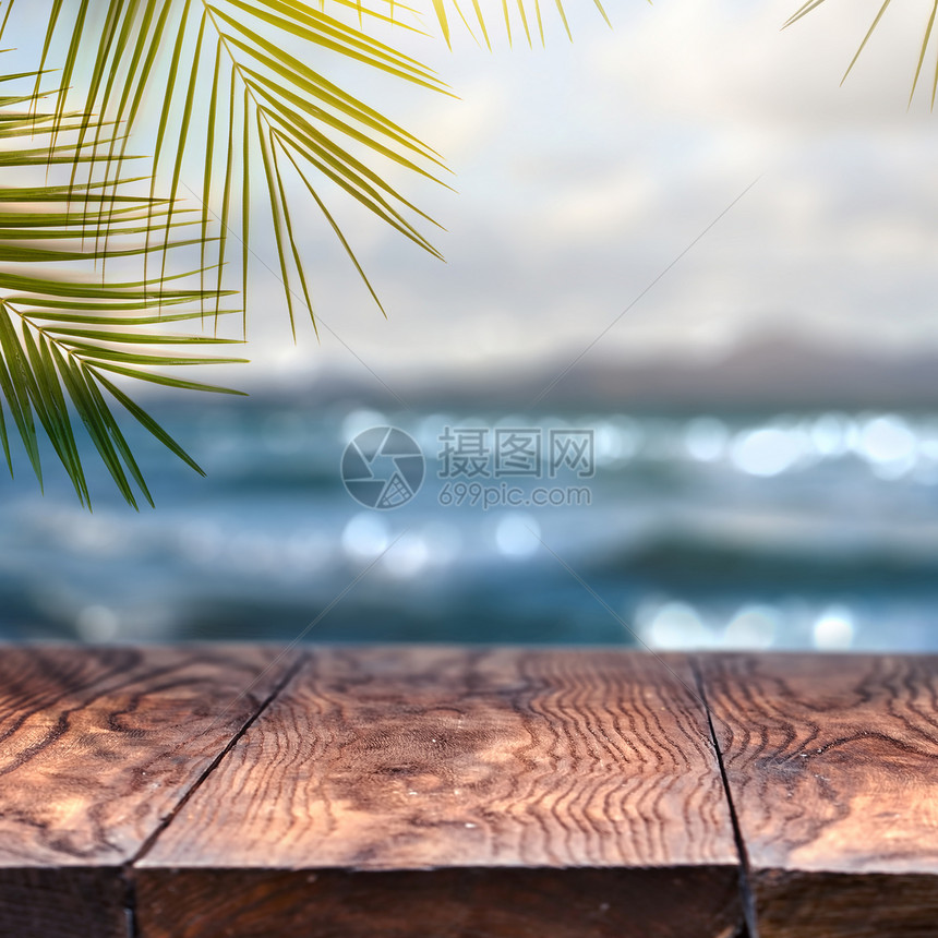 沙滩背景棕榈椰子叶和旧木板以模糊的沙滩背景和观点为顶端以模糊的沙滩背景为顶端并展望促进产品概念夏季放松和聚会旧木板以模糊的海滩背图片