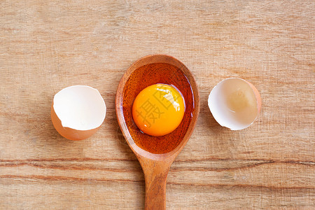 木桌背景木勺上的蛋黄图片