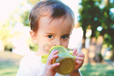 在公园里喝奶瓶的可爱小男孩图片