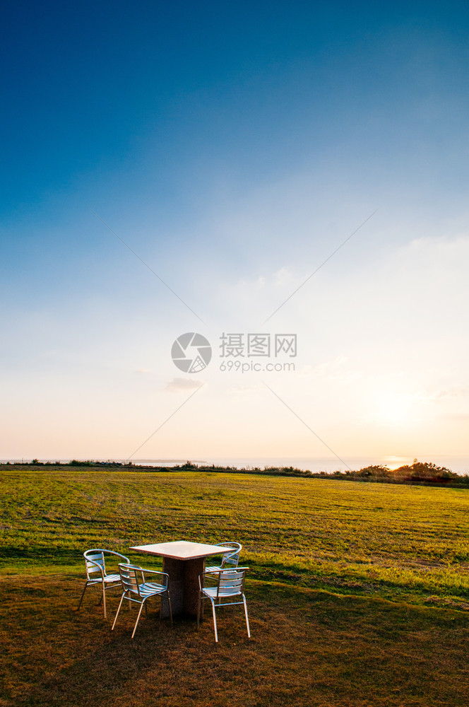 日落或出时在本霍基那瓦岛的Ishigak岛野餐桌下在海边宽阔的草地海野餐桌图片