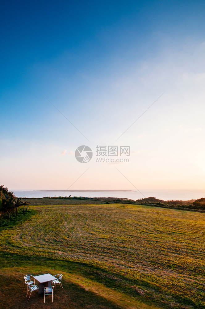 日落或出时在本霍基那瓦岛的Ishigak岛野餐桌下在海边宽阔的草地海野餐桌图片