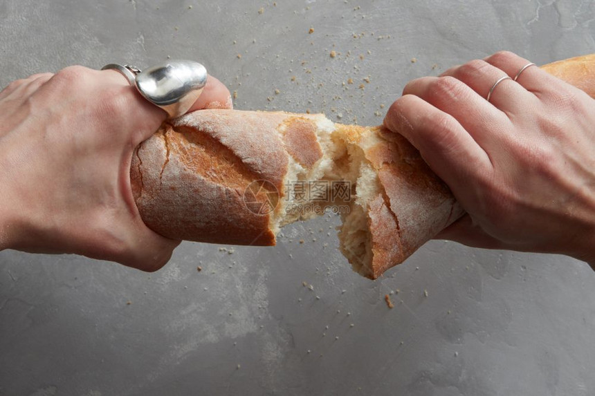 女在灰石背景上用新鲜的烤面包打断手图片