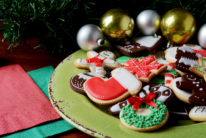 木制桌子上带有彩色圣诞饼干的盘子xmas假日概念图片
