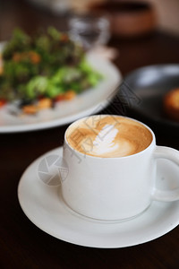卡布奇诺或拿铁咖啡用店木桌的牛奶制成咖啡图片