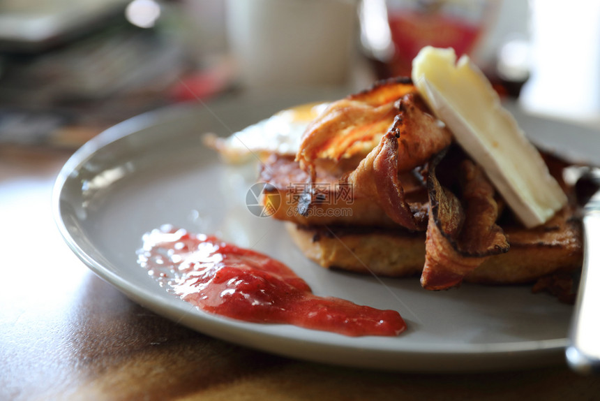 早餐法式烤面包加培根鸡蛋和奶酪加果酱在木桌背景上图片