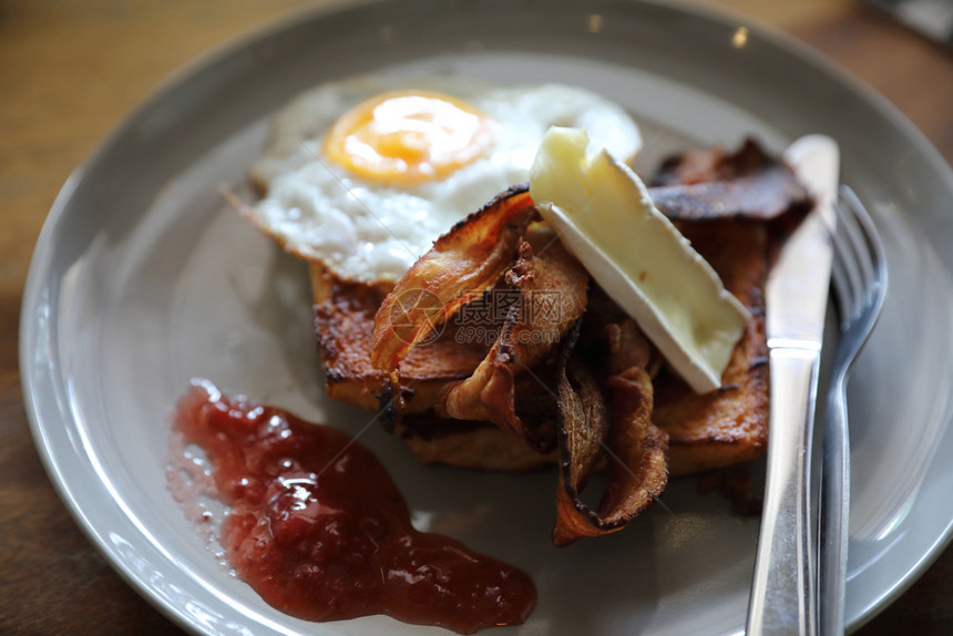 早餐法式烤面包加培根鸡蛋和奶酪加果酱在木桌背景上图片