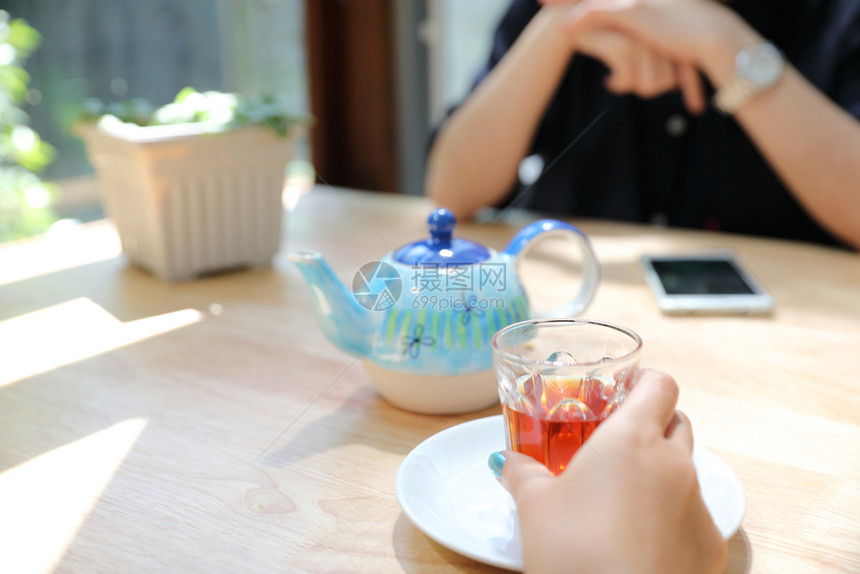 在咖啡店里妇女手牵在咖啡店里讲茶和智能电话图片