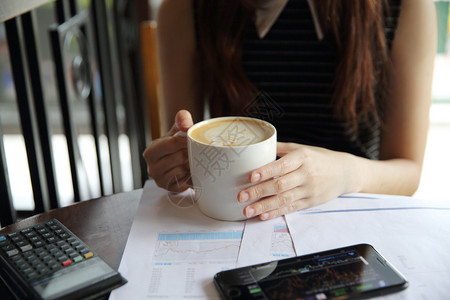 女子一边喝着咖啡一边用手机看电视图片