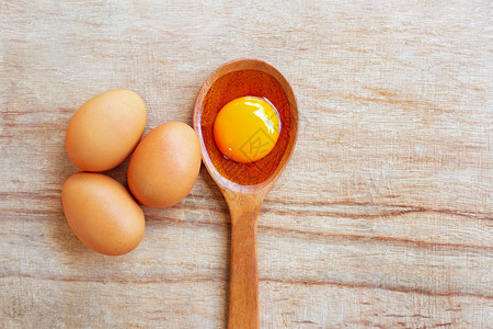 勺子上的蛋黄和旁边的三个鸡蛋图片