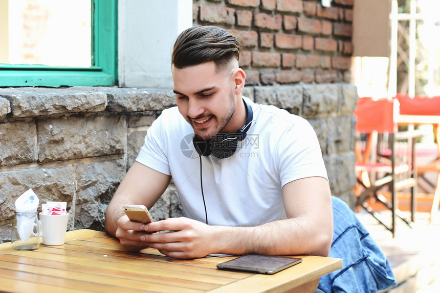 年轻拉丁男子在户外打手机的肖像图片