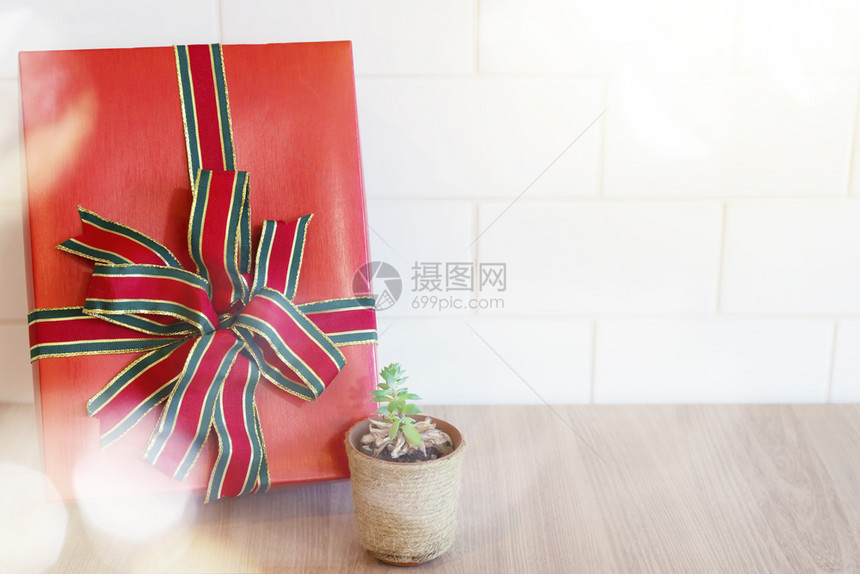 红礼盒紧贴在木桌和白墙上的小树锅可以用于新年快乐圣诞生日和另一个庆祝背景图片