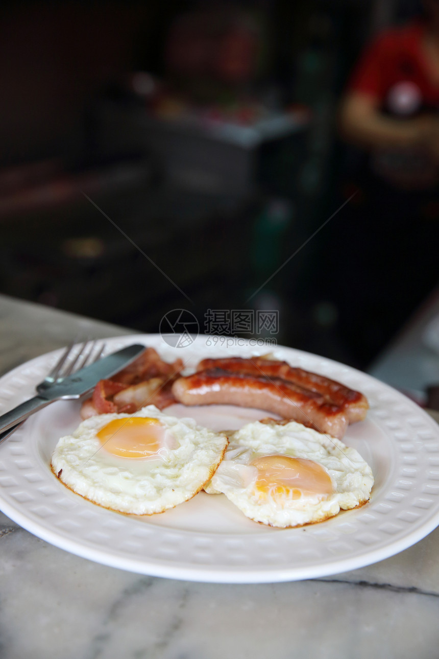 圆白盘上的煎鸡蛋和香肠培根图片
