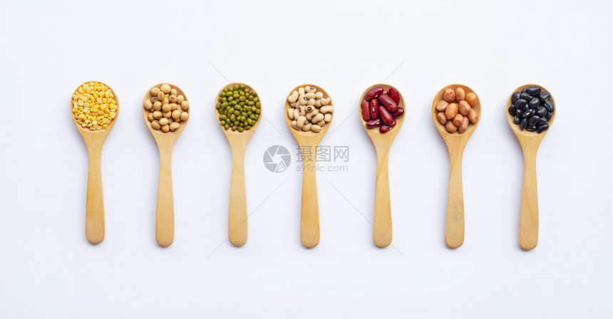 木勺白色背景上的不同种类豆图片