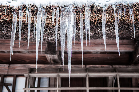 在日本冬天的冰棒挂在屋顶的阴沟上高清图片
