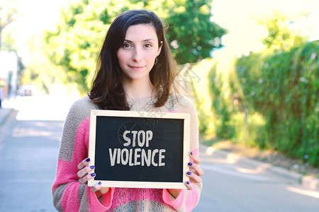年轻漂亮的女人拿着黑板写着制止暴力户外图片