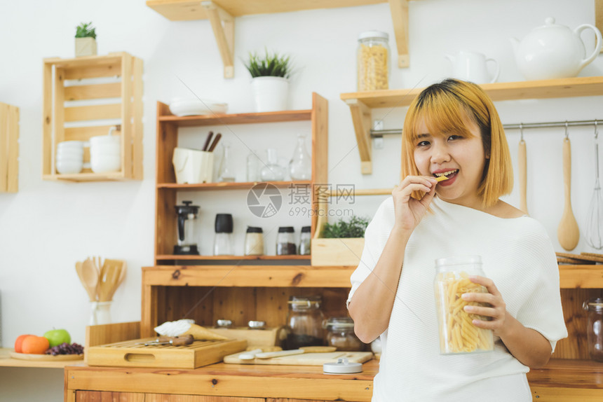 年轻女在厨房吃零食图片