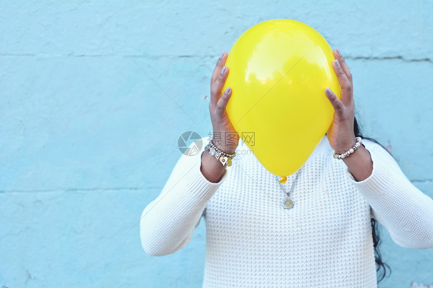 在街上用气球盖着头的年轻女子图片