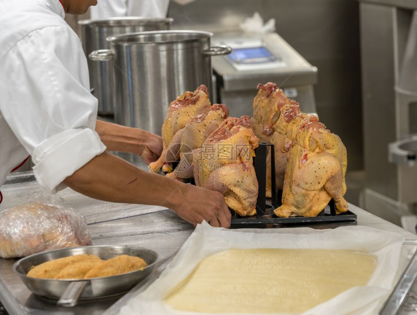 在餐馆的商业不锈钢厨房里做鸡的师图片