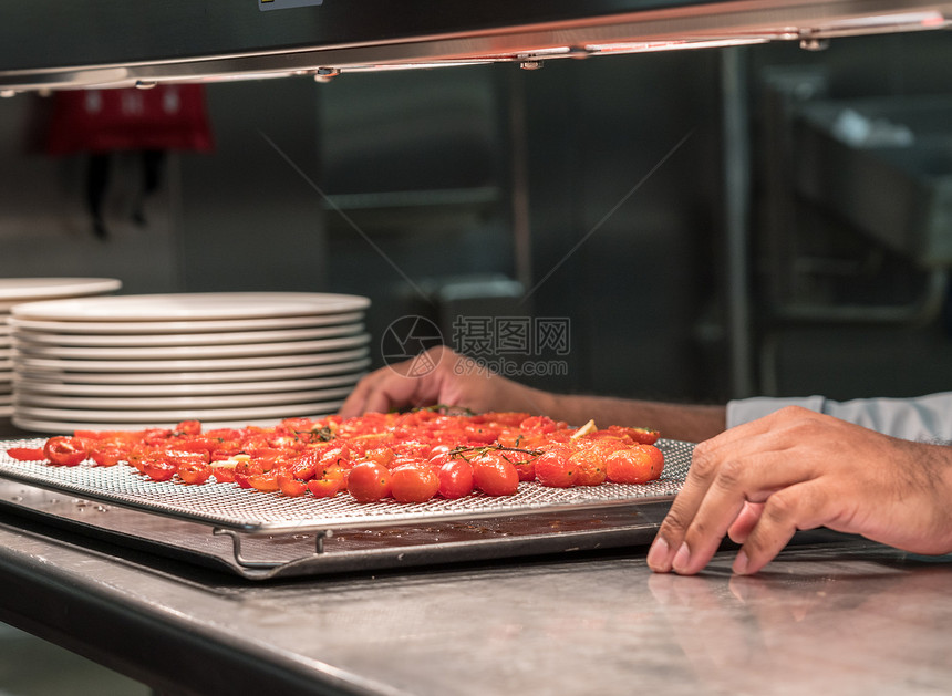 烹饪厨师在餐馆商业不锈钢厨房做烤西红柿在现代商业厨房做烤西红柿图片