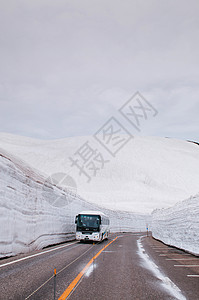 日本雅潘的公交行驶于雪墙之间道路视图图片