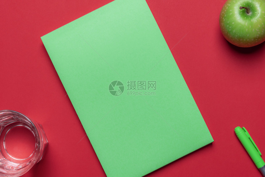 红色桌子的顶部视图绿色空笔记本一杯水绿色苹果饮食背景回到学校家庭办公桌图片