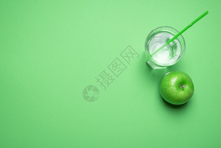 上方是一片绿苹果靠近一杯有稻草的水绿色背景最低要求戒毒概念健康饮食素背景图片