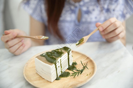 年青的轻女人吃绿茶便蛋糕甜食图片