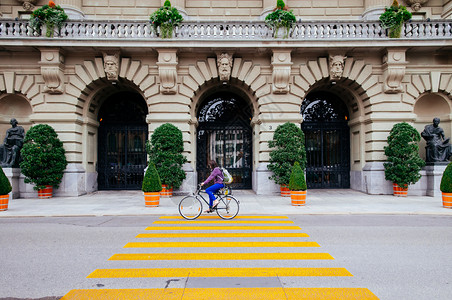 瑞士当地妇女骑着自行车经过斑马线图片