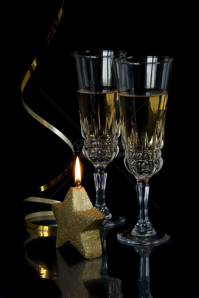喜庆成份两杯水晶香槟金蛇纹和一颗恒星形状的燃烧蜡烛在黑色背景上图片