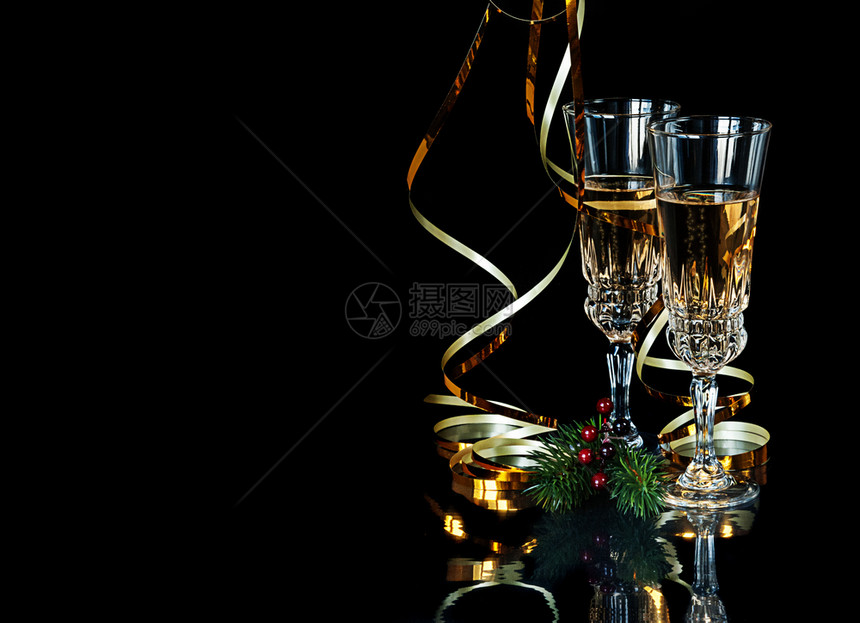 黑色背景上的节日组成两杯玻璃晶香槟金蛇绿树枝和红荷利果并带有复制空间图片
