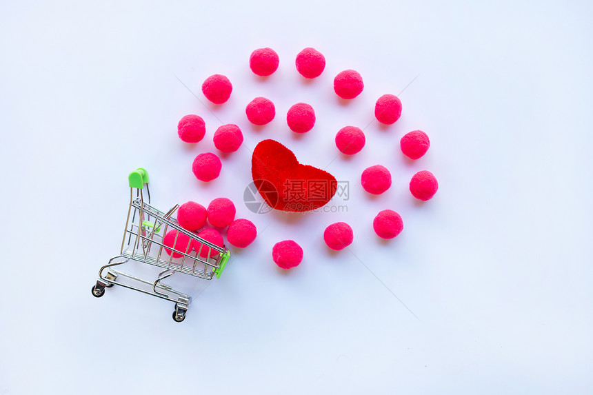红色心脏和小粉球白色背景上有购物车复制空间情人节的概念背景图片