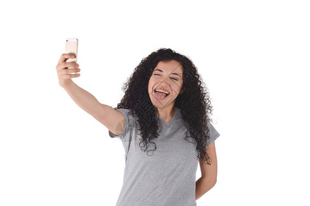 年轻拉丁女人用智能手机在室内自拍孤立的白色背景图片