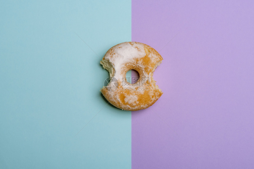 美味甜圈从两个站点咬下来蓝色和紫背景图片