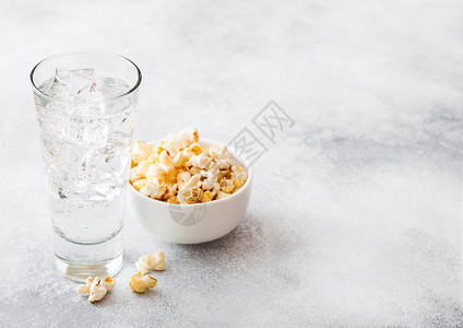 一杯柠檬汁苏打饮料冰块和白碗爆米花零食在石器厨房背景图片