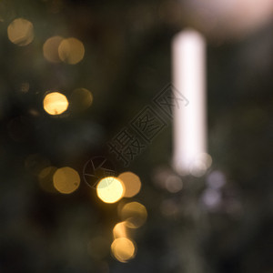 以白色蜡烛在fir树上点亮温暖的抽象圣诞灯光图片