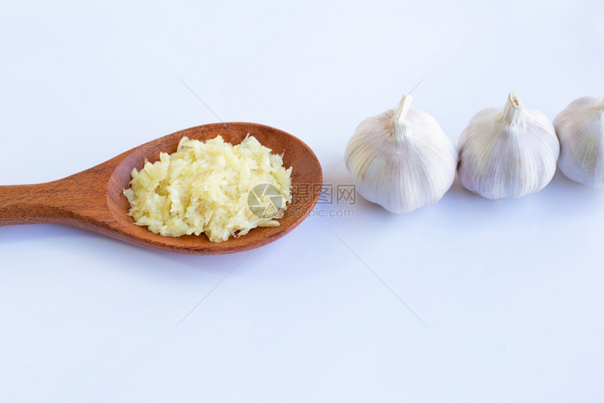 木勺上的新切片大蒜和头白色背景上图片