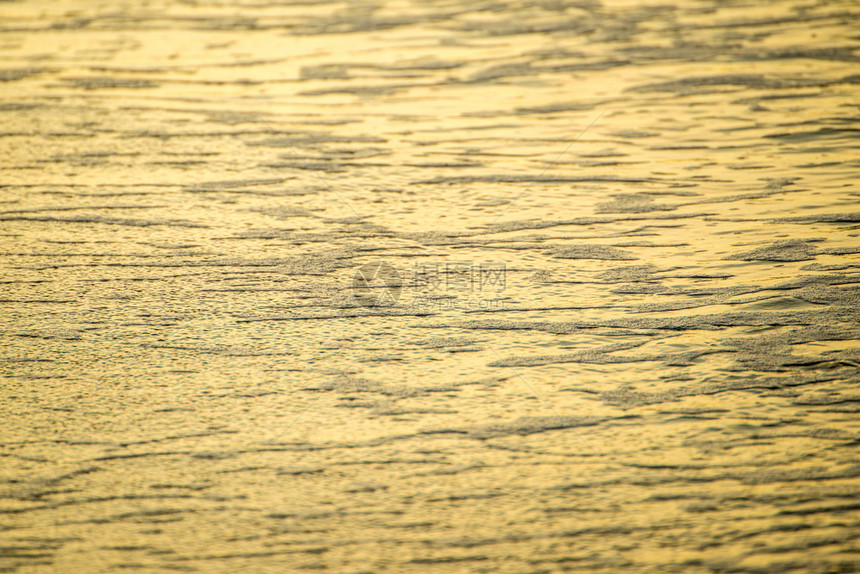 海中的水以温暖日落光照亮海浪图片
