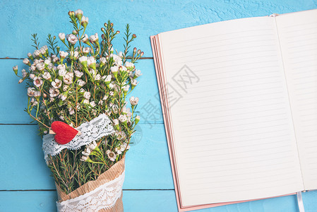 白色小花装在旧纸和丝带上靠近空议程放在蓝色的桌子上面视图母亲日框架春季背景背景图片