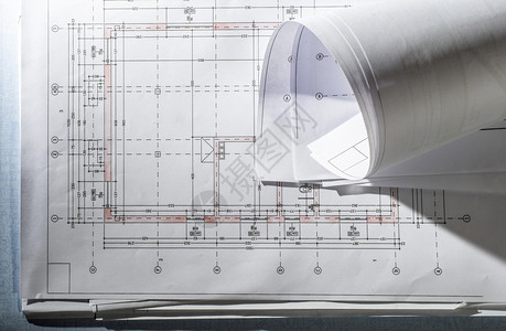 建筑师办公桌上的蓝图建筑项目堆叠并铺设了自然窗口灯光的建筑项目和概念图片