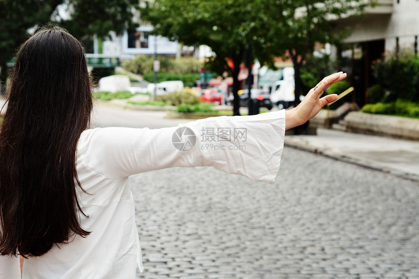 年轻妇女在街上叫计程车抬起手臂图片