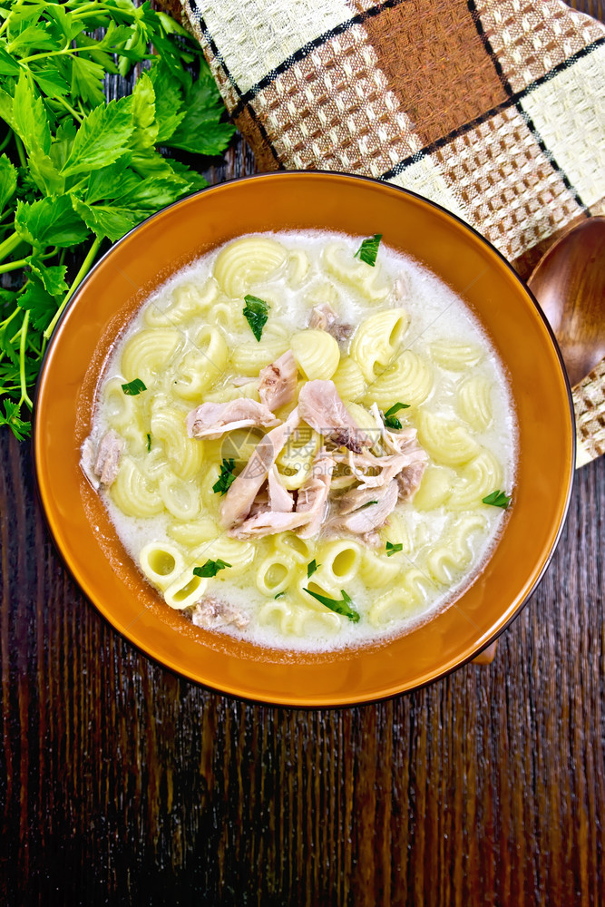 鸡肉汤意大利面和奶油及粘土板毛巾面食木板上勺子的肉汤面粉及奶油和香肠图片