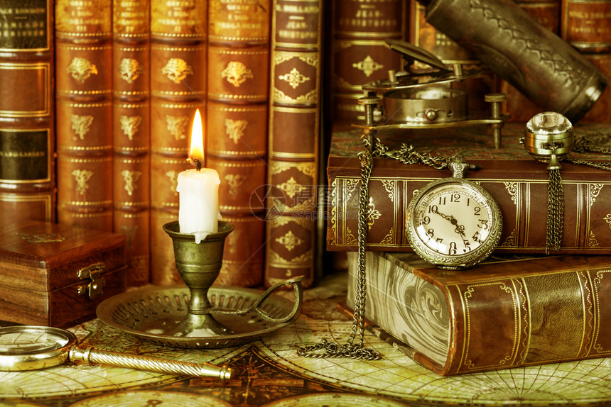古老的口袋手表和在旧的烛台烧蜡都在古董书的背景上图片