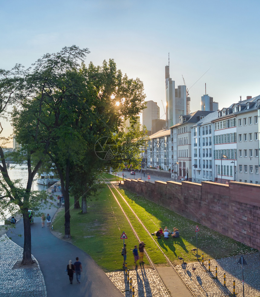 人们在城市堤防的绿草坪上行走和放松晚上阳光明亮棕褐色德国图片