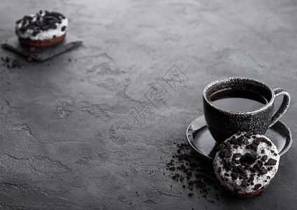 黑咖啡杯有碟子和甜圈黑石餐桌背景上有黑饼干文本空间图片