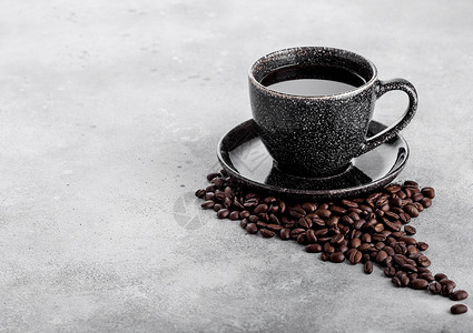 黑咖啡杯配有碟子和新鲜咖啡豆放在石餐桌背景上图片