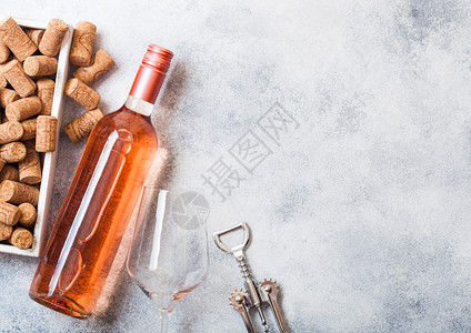 酒箱和粉红玫瑰葡萄酒的瓶子里面装有软木箱和开瓶器放在石头厨房桌背景上背景